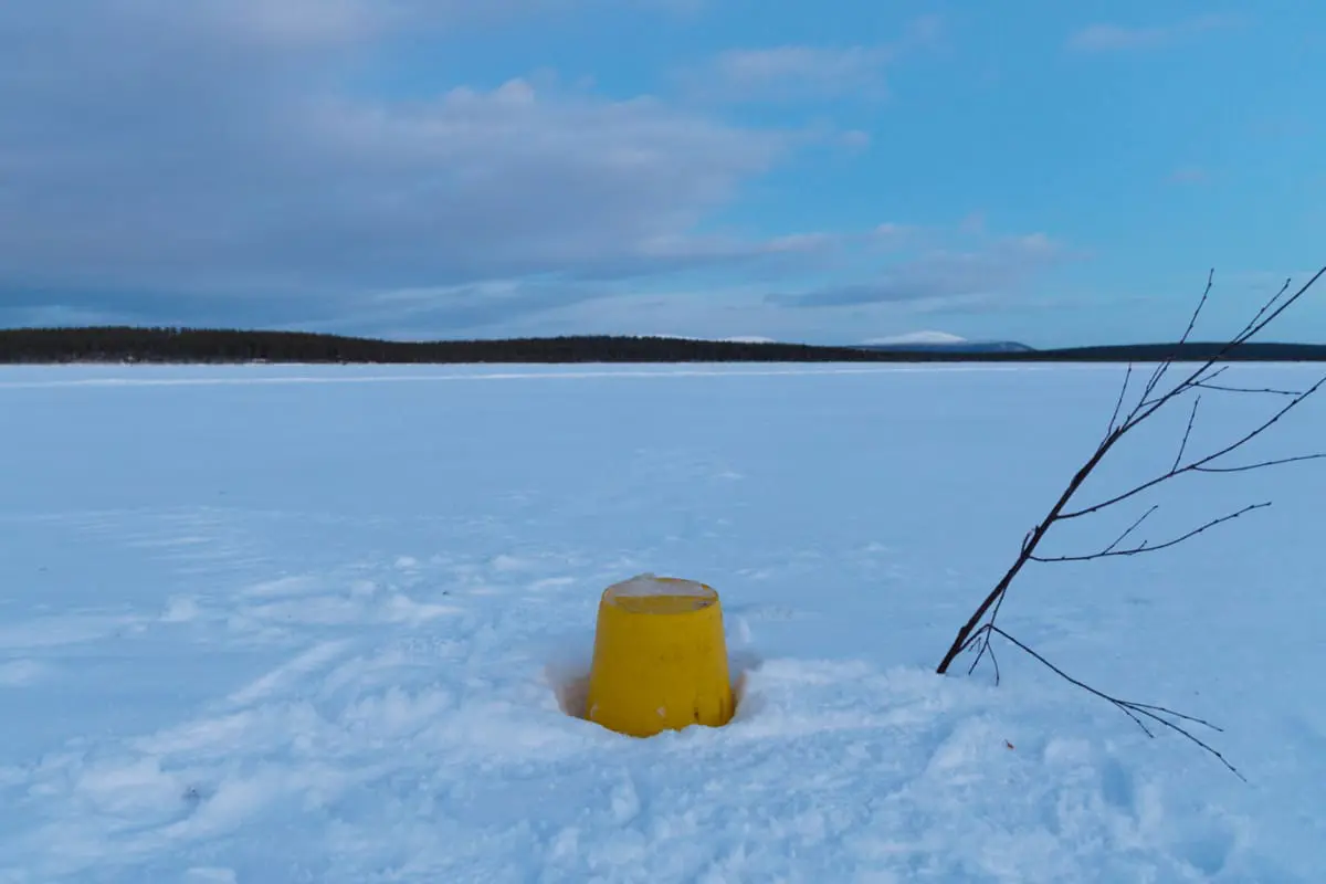 Ein Eimer markiert das Loch im Fluss, um Wasser zu holen