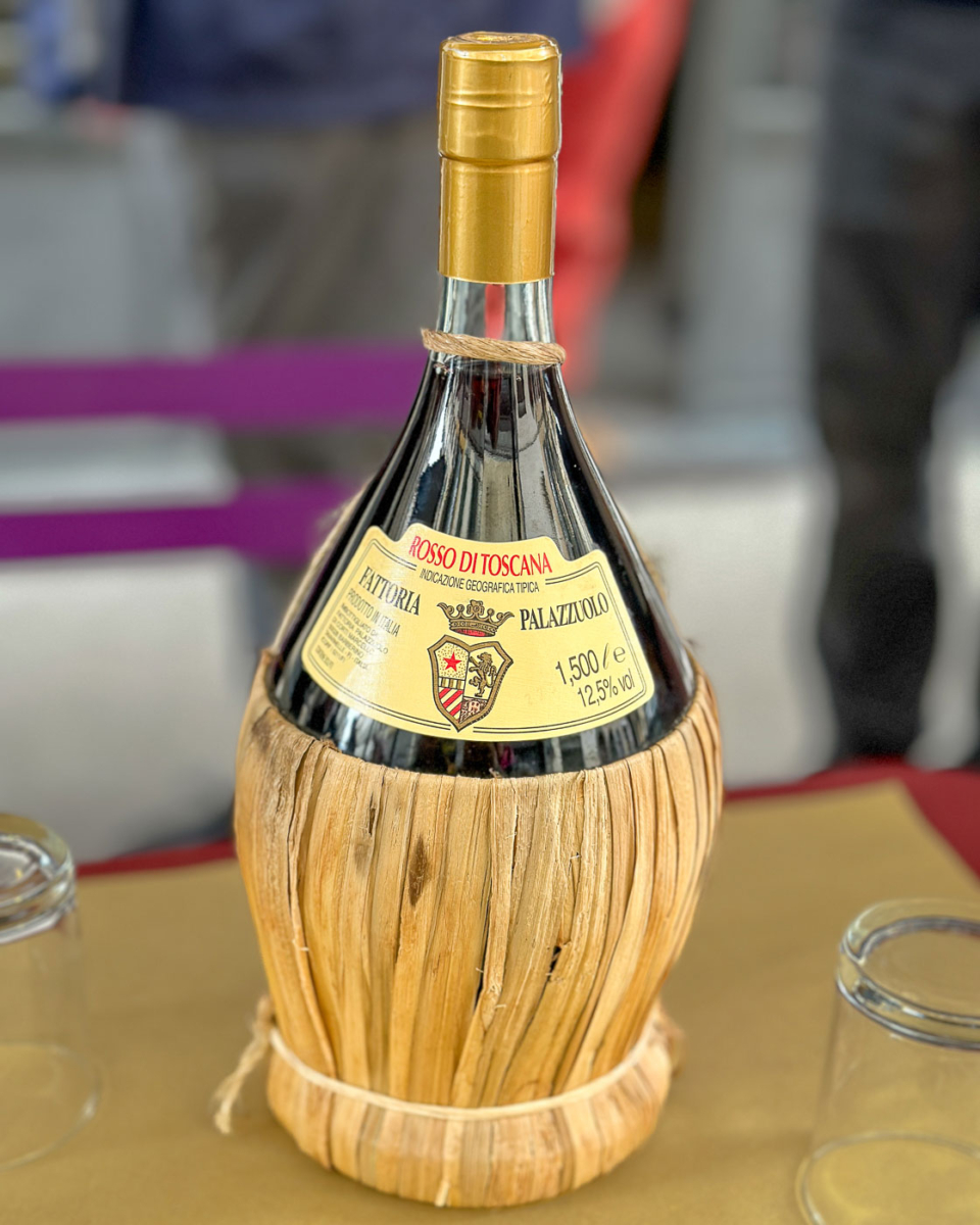 Eine Flasche passt genau durch ein Weinfenster "Buchetta del Vino" in Florenz